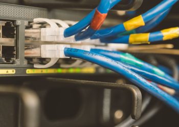 Network switch and blue ethernet cable with white tips connected to system for maintenance